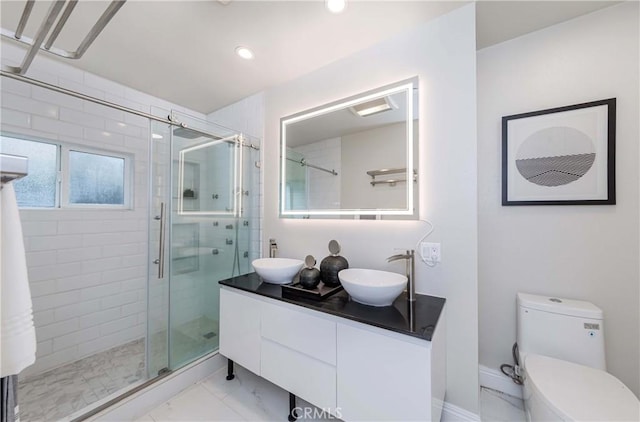 bathroom featuring a stall shower, toilet, marble finish floor, and a sink