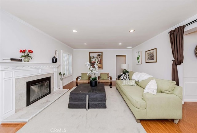 living area featuring a fireplace, recessed lighting, wood finished floors, and ornamental molding