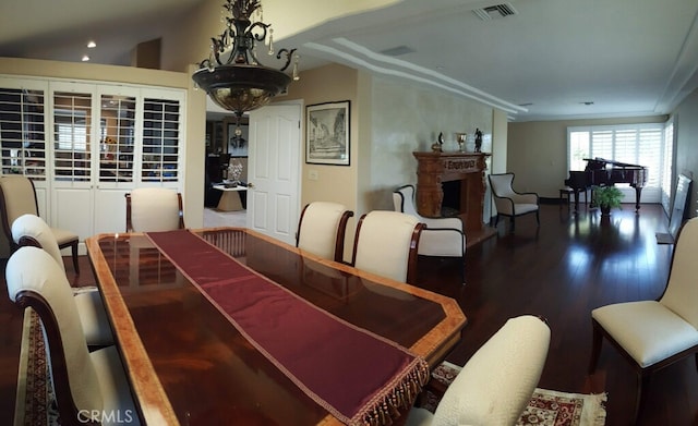 dining area with visible vents, lofted ceiling, wood finished floors, and a fireplace