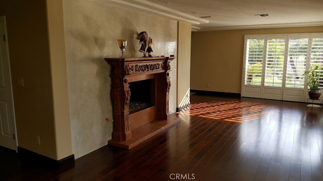 unfurnished living room with visible vents, baseboards, a fireplace with raised hearth, and dark wood-style flooring