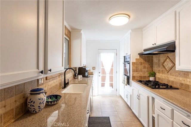 kitchen with gas stovetop, oven, a sink, white cabinets, and under cabinet range hood