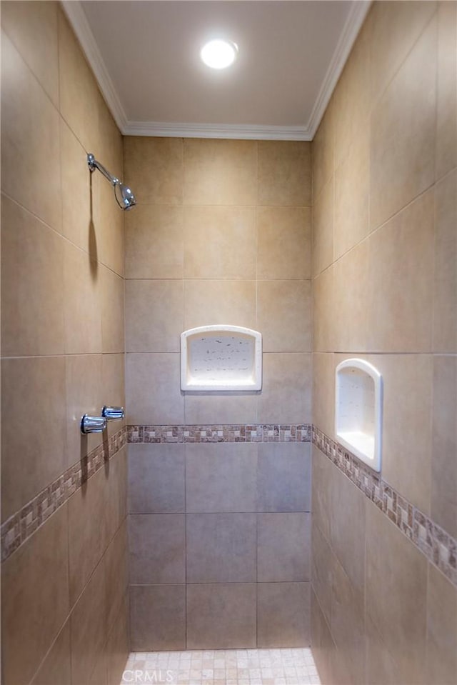 bathroom featuring a tile shower and ornamental molding