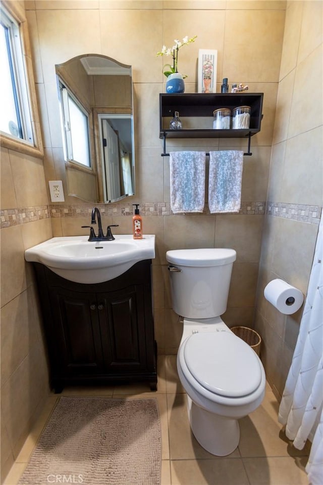 bathroom featuring tile patterned flooring, toilet, vanity, and tile walls