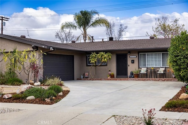 ranch-style home featuring concrete driveway, an attached garage, roof with shingles, and stucco siding