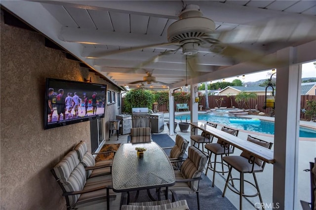 view of patio / terrace featuring a ceiling fan, outdoor dining area, a fenced backyard, a pool with connected hot tub, and a grill