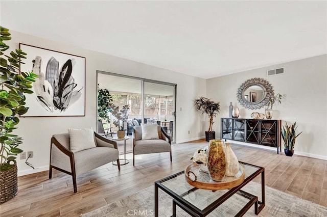 living room with visible vents, baseboards, and light wood-style floors