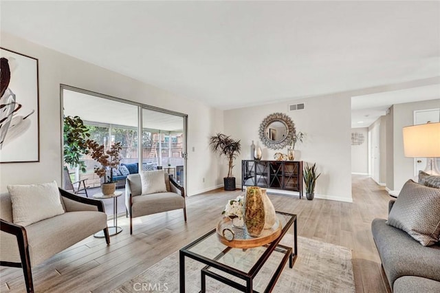 living room with visible vents, baseboards, and light wood finished floors