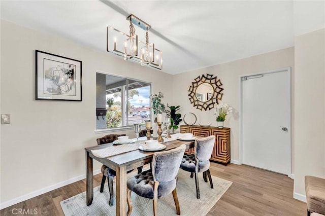 dining room with a chandelier, light wood-type flooring, and baseboards