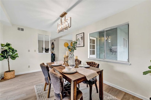 dining room with visible vents, light wood-style flooring, an inviting chandelier, and baseboards