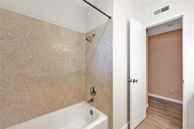 full bath featuring tub / shower combination, visible vents, baseboards, and wood finished floors