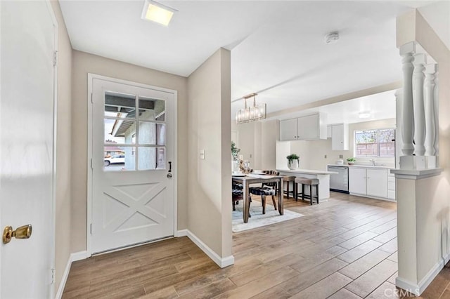 entrance foyer with baseboards, light wood-style floors, and an inviting chandelier