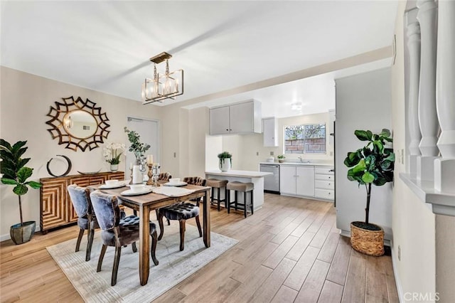 dining space with baseboards, a notable chandelier, and light wood finished floors