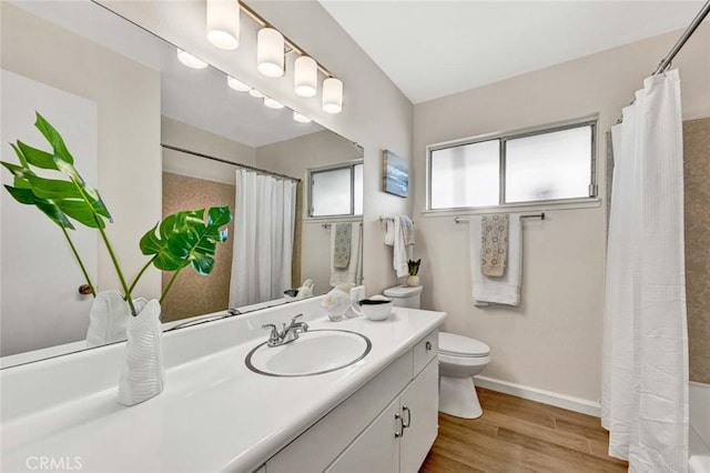 bathroom featuring toilet, wood finished floors, a shower with shower curtain, baseboards, and vanity