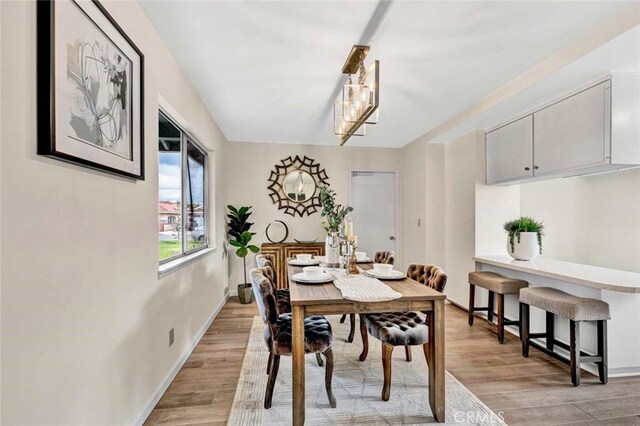 dining area with an inviting chandelier, light wood-style flooring, and baseboards