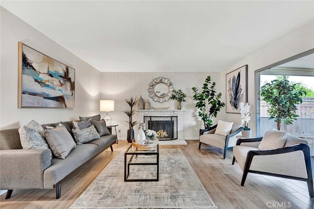 living area with a brick fireplace, baseboards, and wood finished floors