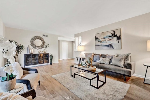 living room with visible vents, baseboards, and wood finished floors