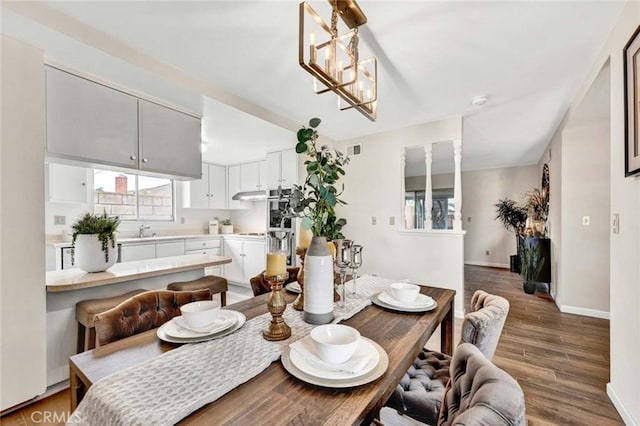 dining area with an inviting chandelier, wood finished floors, and baseboards