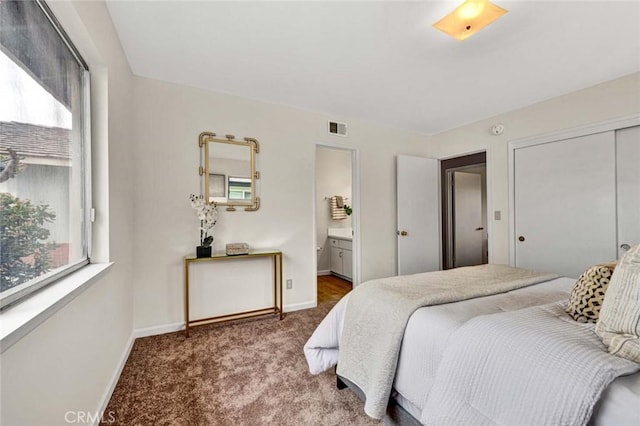 carpeted bedroom with ensuite bath, baseboards, visible vents, and a closet