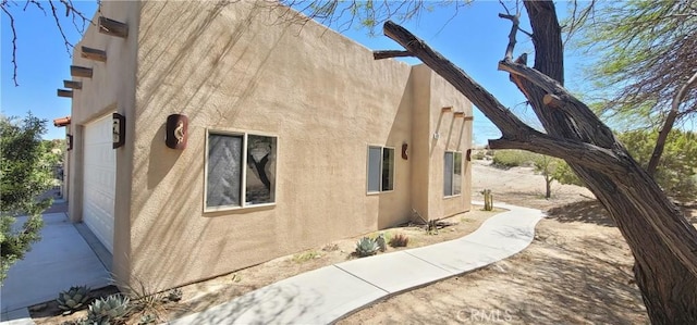 view of side of home with a garage and stucco siding