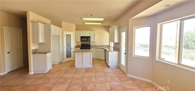 kitchen with a wealth of natural light, stove, black microwave, and white cabinetry