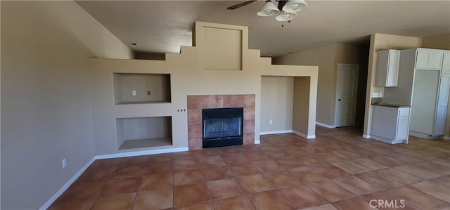 unfurnished living room with light tile patterned flooring, a ceiling fan, baseboards, and a tile fireplace