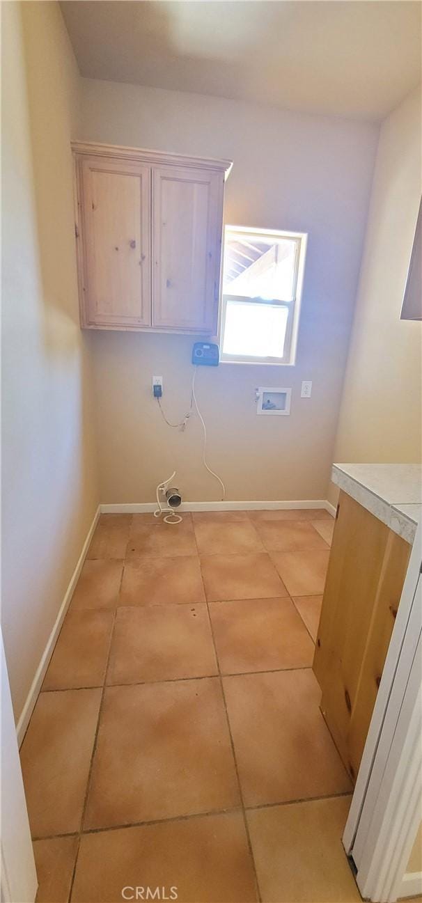 clothes washing area with light tile patterned floors, laundry area, hookup for a washing machine, and baseboards