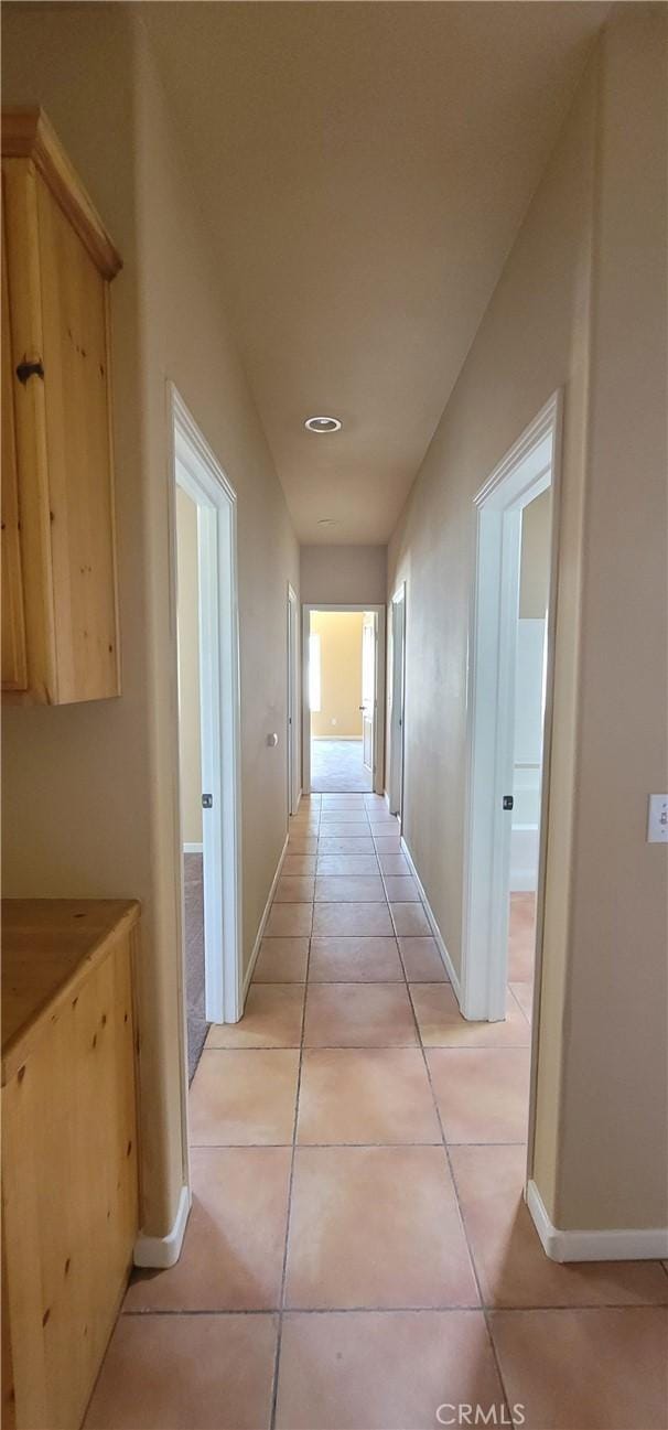 corridor with light tile patterned flooring and baseboards