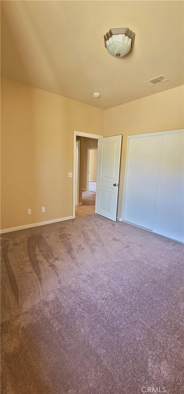 unfurnished bedroom featuring visible vents, carpet floors, and baseboards