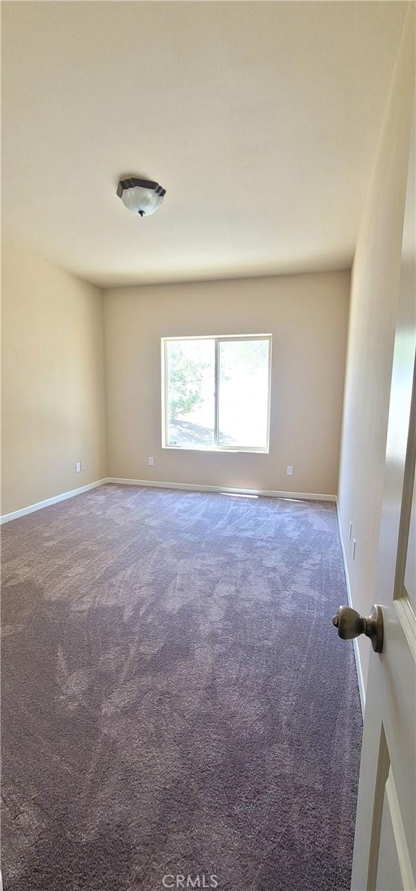 carpeted empty room featuring baseboards