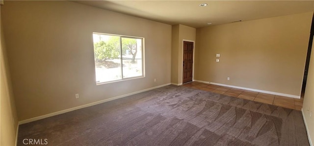 carpeted spare room featuring tile patterned flooring and baseboards