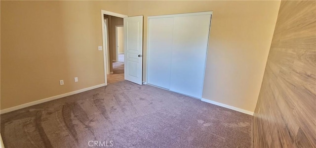 unfurnished bedroom with carpet flooring, baseboards, and a closet