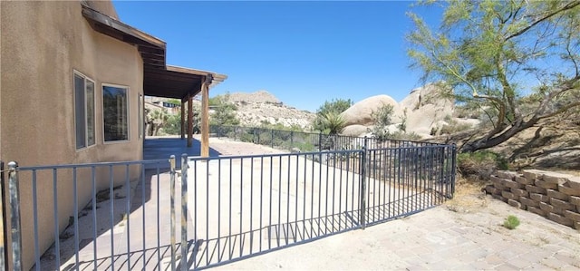 view of gate with a patio, fence, and a mountain view