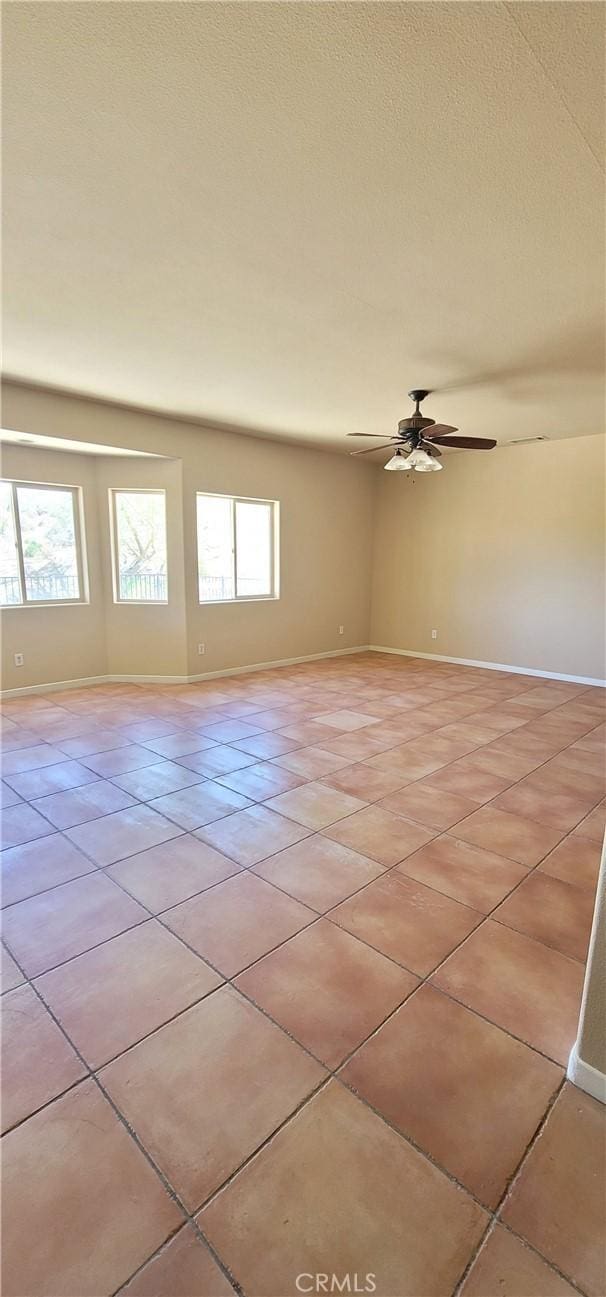 unfurnished room with light tile patterned floors, a healthy amount of sunlight, and ceiling fan