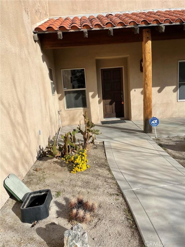 doorway to property with stucco siding and a tiled roof