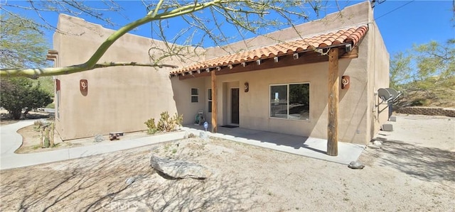 back of house featuring a tiled roof, a patio area, and stucco siding