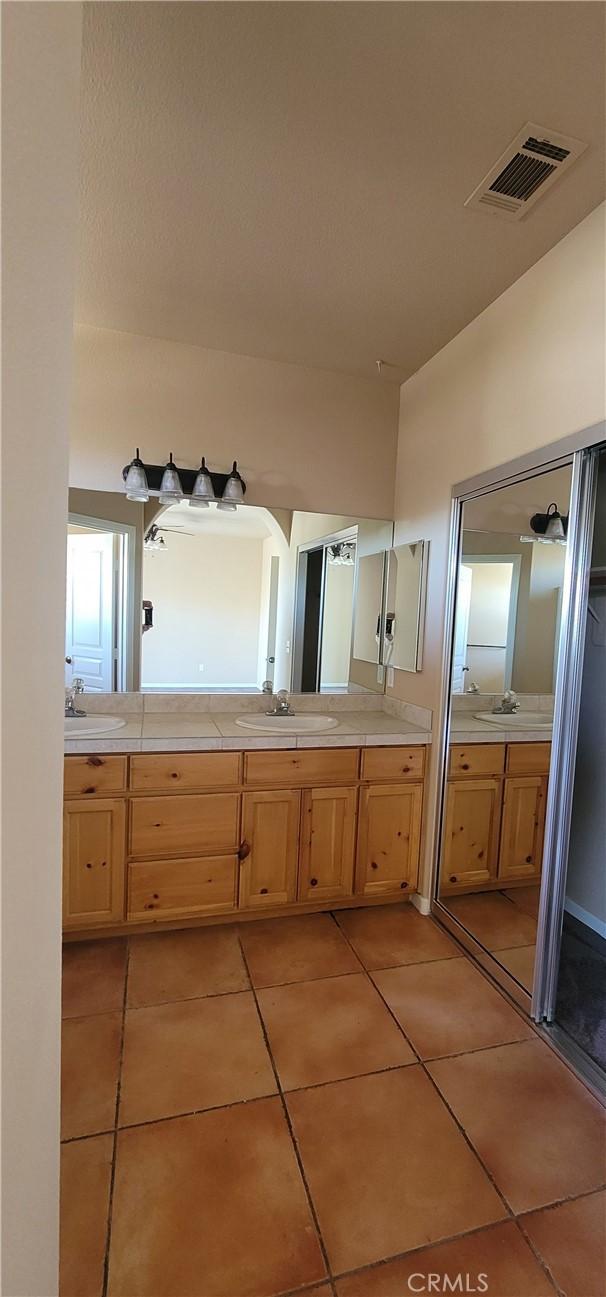 bathroom featuring tile patterned flooring, double vanity, visible vents, and a sink