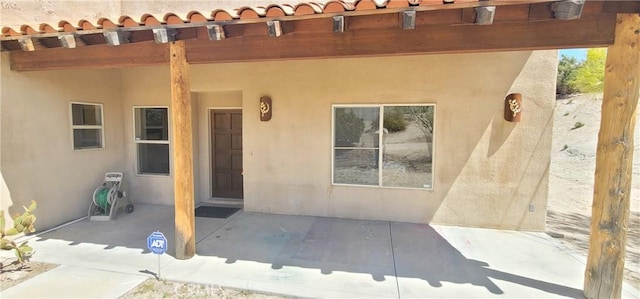 property entrance with stucco siding and a patio area