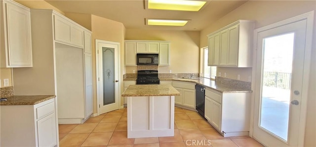 kitchen with light tile patterned flooring, a sink, black appliances, white cabinets, and a center island