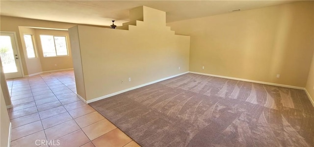 carpeted empty room featuring baseboards and tile patterned flooring