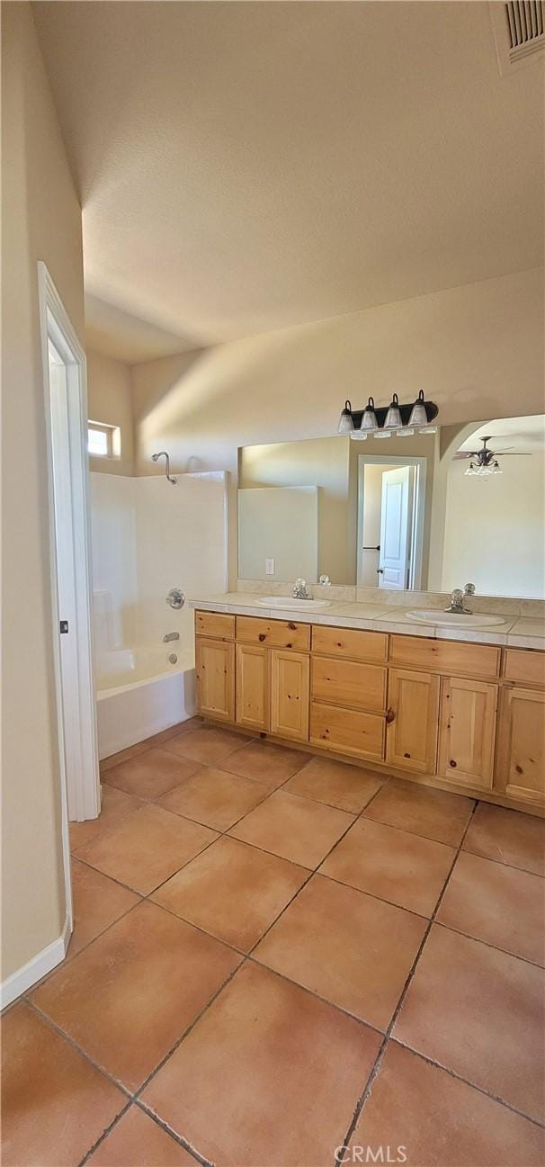 full bath with a sink, double vanity, and tile patterned floors