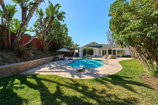 view of pool with a fenced in pool, fence, a yard, a diving board, and a patio area