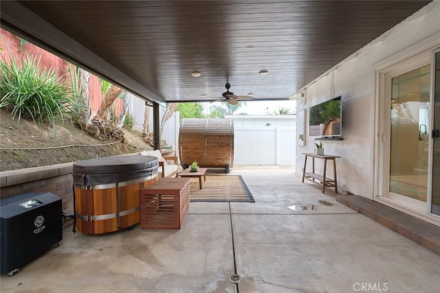 view of patio with a hot tub, a ceiling fan, and fence