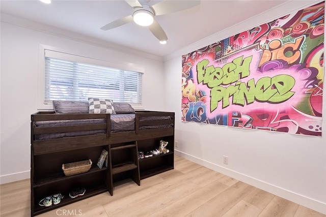 bedroom with a ceiling fan, crown molding, baseboards, and wood finished floors