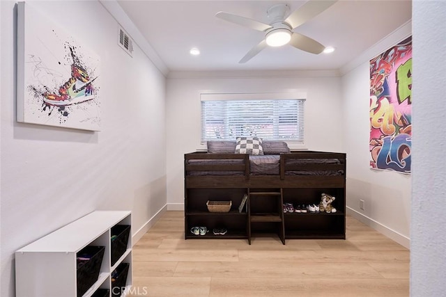 bedroom with visible vents, baseboards, crown molding, and light wood finished floors