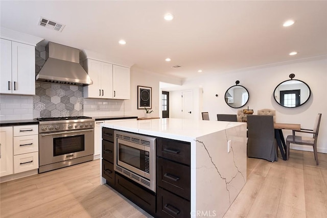 kitchen with white cabinets, wall chimney exhaust hood, visible vents, and appliances with stainless steel finishes