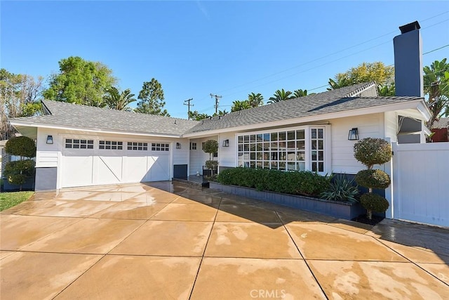 ranch-style home featuring a chimney, driveway, an attached garage, and fence