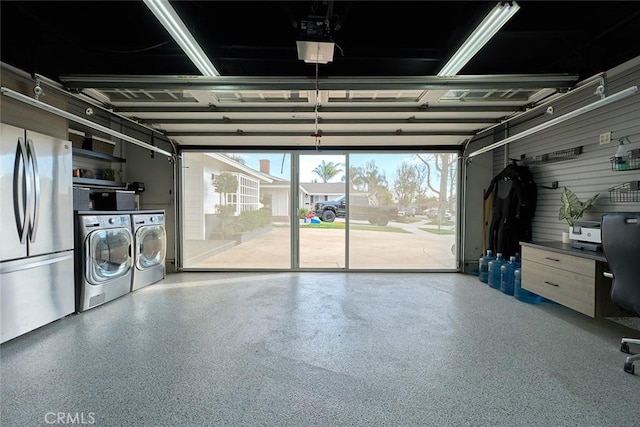 garage with a garage door opener, freestanding refrigerator, and washing machine and clothes dryer