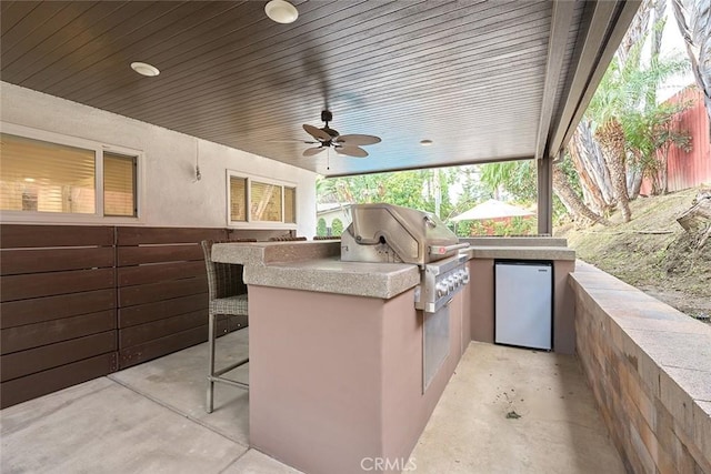 view of patio / terrace featuring exterior kitchen, a ceiling fan, and a grill