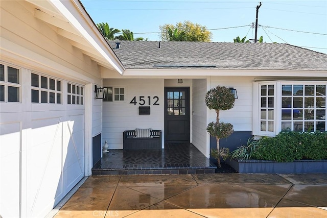 doorway to property with roof with shingles and an attached garage