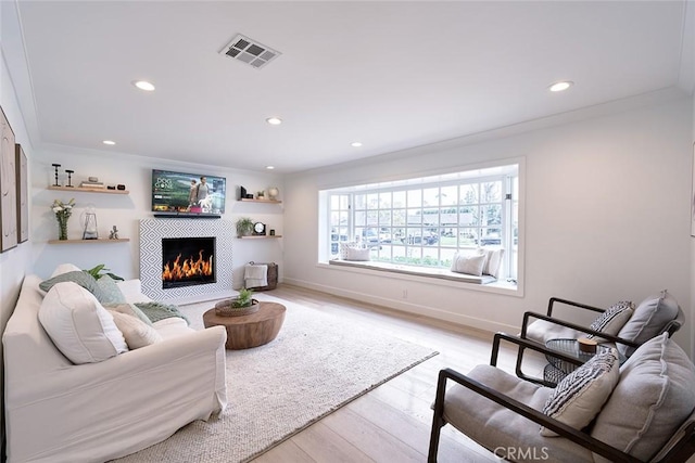 living area with visible vents, baseboards, light wood-type flooring, recessed lighting, and a fireplace